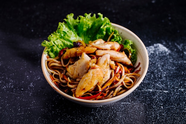 Chinese noodles inside bowl with fillet and lettuce.