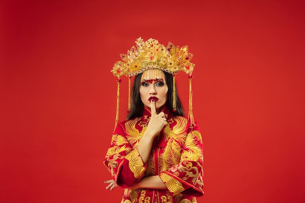 빨간색 배경 위에 스튜디오에서 중국 전통 우아한 여자. 민족 의상을 입고 아름 다운 소녀입니다. 구정, 우아함, 은혜, 연기자, 공연, 춤, 배우, 드레스 컨셉