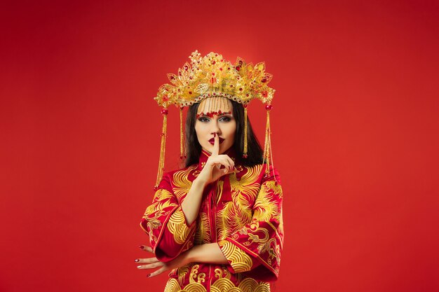 Chinese traditional graceful woman at studio over red wall