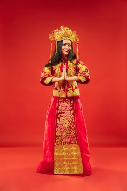 Chinese traditional graceful woman at studio over red.