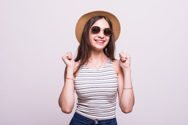 Солнечные очки шляпы китайской женщины нося стоя над изолированный белый праздновать предпосылки удивили и изумили для успеха с глазами поднятыми и открытыми. Концепция победителя.