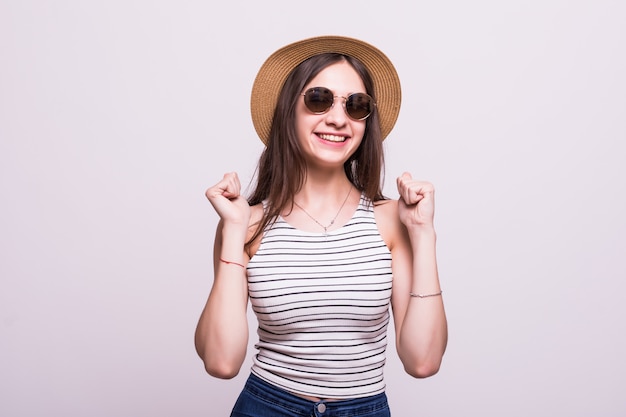 Chinese woman wearing hat sunglasses standing over isolated white background celebrating surprised and amazed for success with arms raised and open eyes. Winner concept.