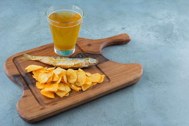 Chips, fish and glass of beer on a board , on the marble background. 