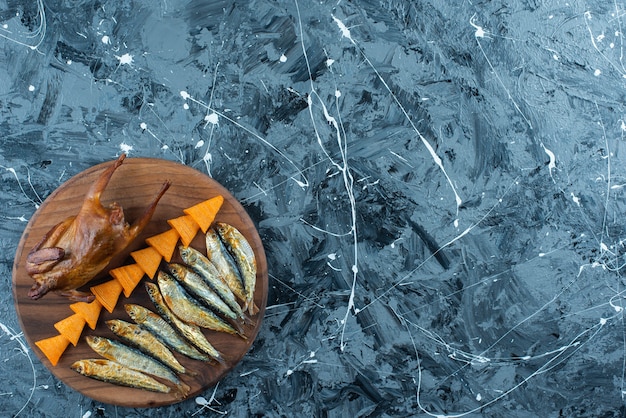 Chips, grill chicken and fish on a board, on the marble background. 