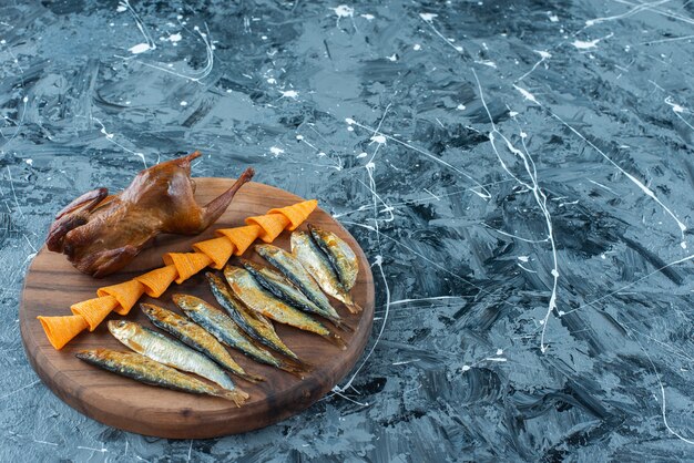 Chips, grill chicken and fish on a board, on the marble background. 