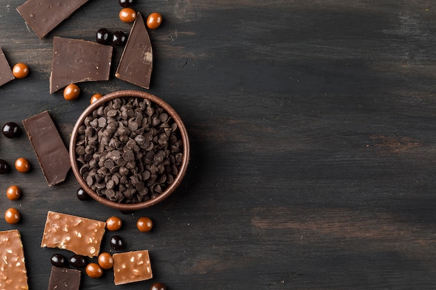 Choco drops with chocoballs and choco bars in a clay bowl on wooden table