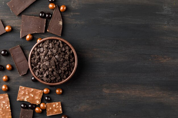 Choco drops with chocoballs and choco bars in a clay bowl on wooden table