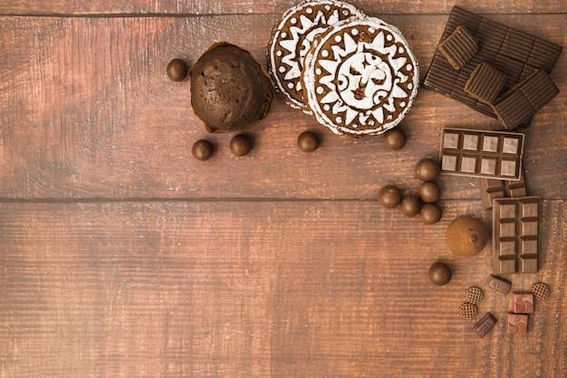 Free photo chocolate ball; bar; muffins and baked cookies on wooden backdrop