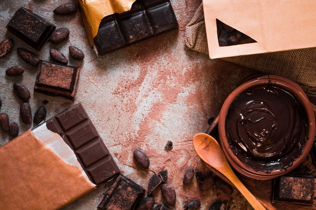 Chocolate bar, cocoa beans, and chocolate cream on table