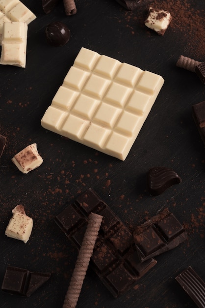 Chocolate bar pieces and candies over wooden surface