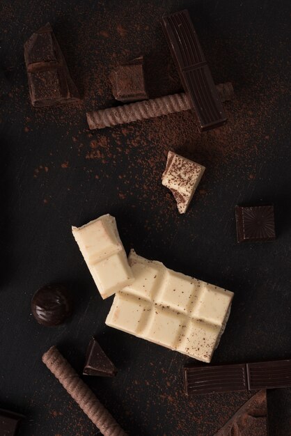 Chocolate bar pieces and candies over wooden surface