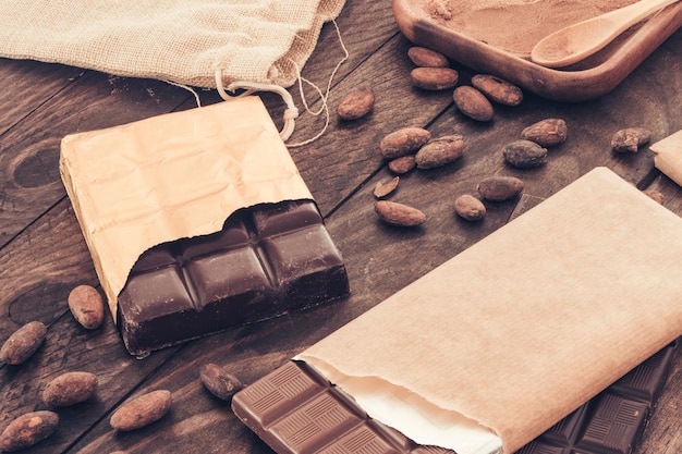 Chocolate bar with cocoa beans on wooden table