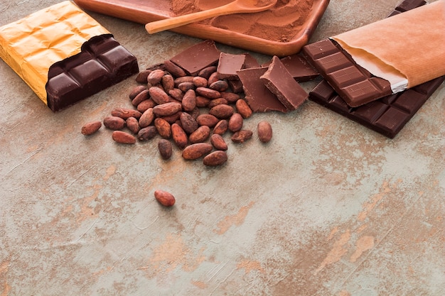 Chocolate bars, cocoa beans and powder on grunge background