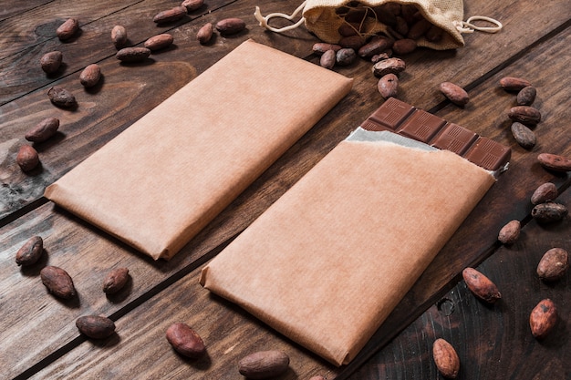Chocolate bars surrounded with cocoa beans on wooden desk