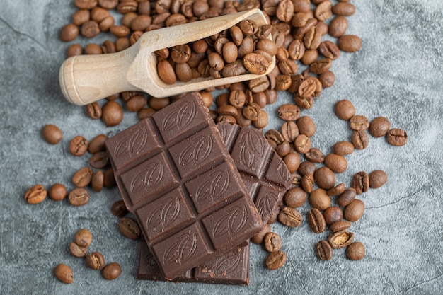 Chocolate bars with coffee beans on gray.