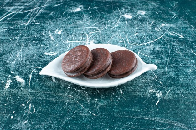 Chocolate biscuit sandwiches on white plate.
