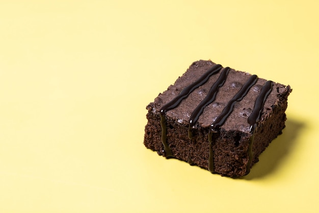 Бесплатное фото Порция шоколадного пирожного на желтом фоне