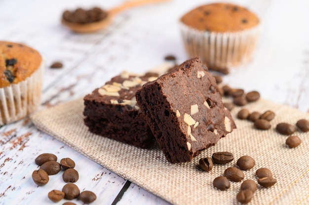 Chocolate brownies on sackcloth and coffee beans on a wooden table.