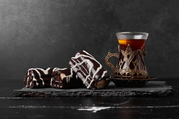 Chocolate brownies on a stone platter with a glass of tea.