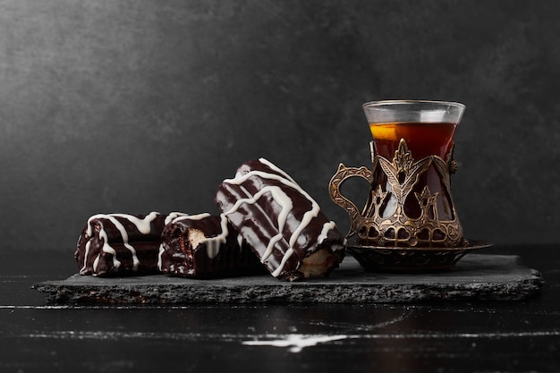 Chocolate brownies on a stone platter with a glass of tea.