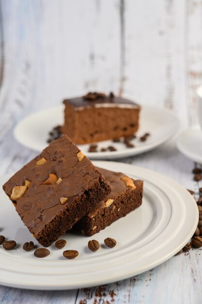 Chocolate brownies on a white plate and coffee beans.