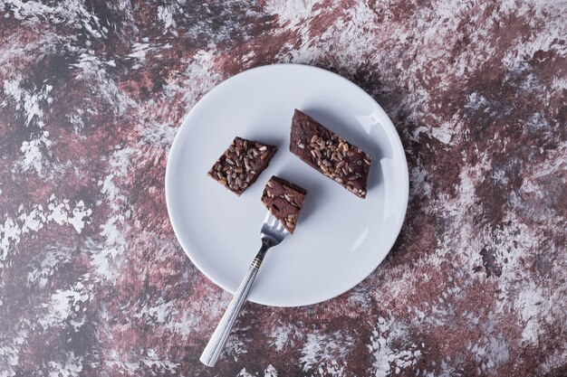 Chocolate brownies in a white plate, top view.