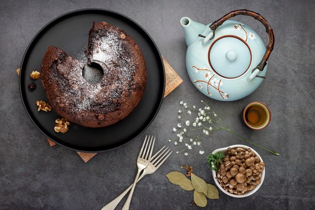 Chocolate cake on a black plate with a tea kettle