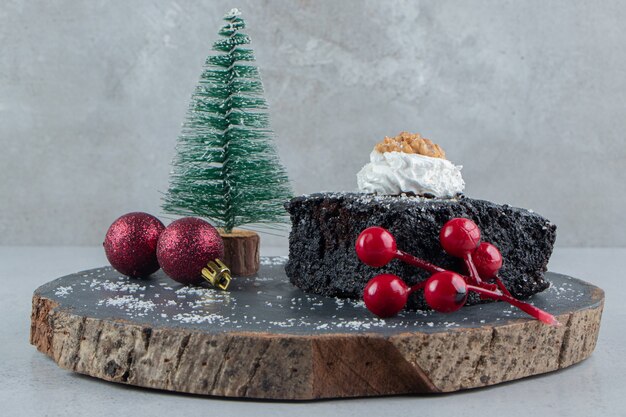 대리석 배경에 나무 보드에 초콜릿 케이크와 크리스마스 장식.