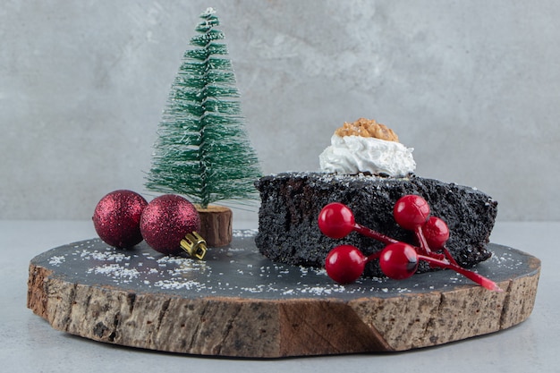 Chocolate cake and christmas decorations on a wooden board on marble background.