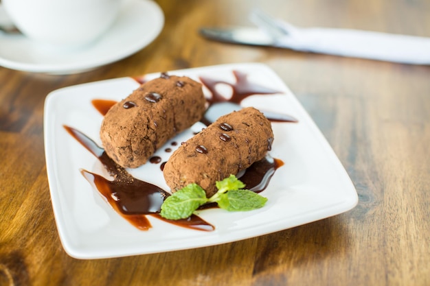 Chocolate cake kartoshka and cappuccino on a wooden table