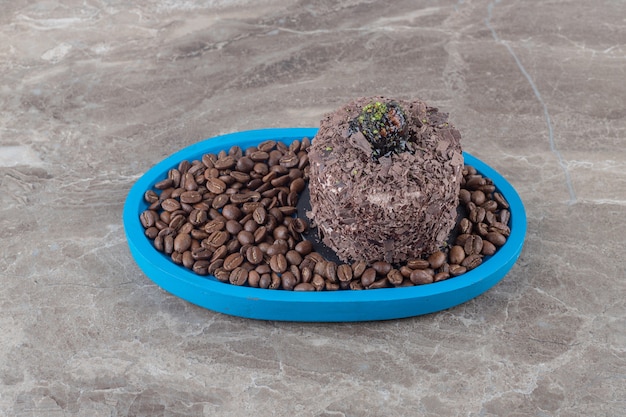 Chocolate cake on a platter full of coffee beans on marble surface