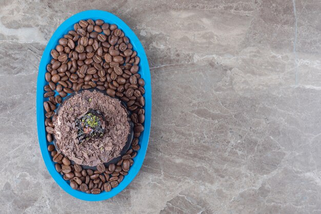 Chocolate cake on a platter full of coffee beans on marble surface