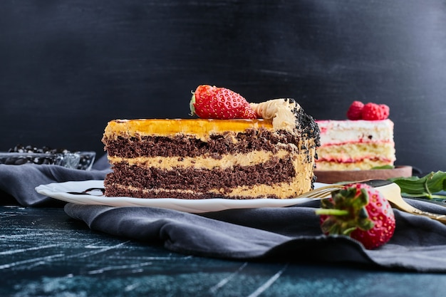 Chocolate cake served with berries on blue background. 