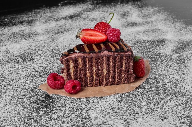 Chocolate cake slice on a wooden platter .