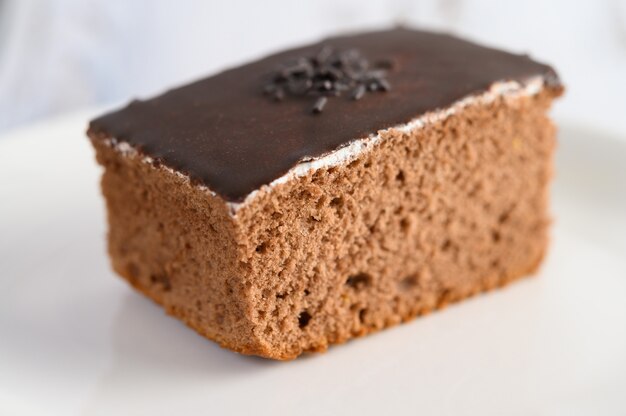 Chocolate cake on a white plate on a wooden table.