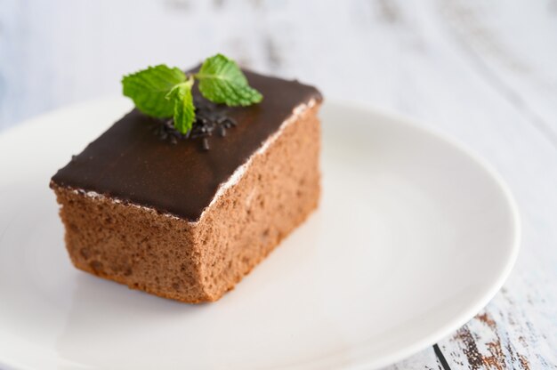 Chocolate cake on a white plate on a wooden table.