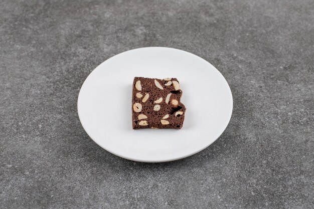 Chocolate cake with peanut. Cake slice on white plate over grey surface