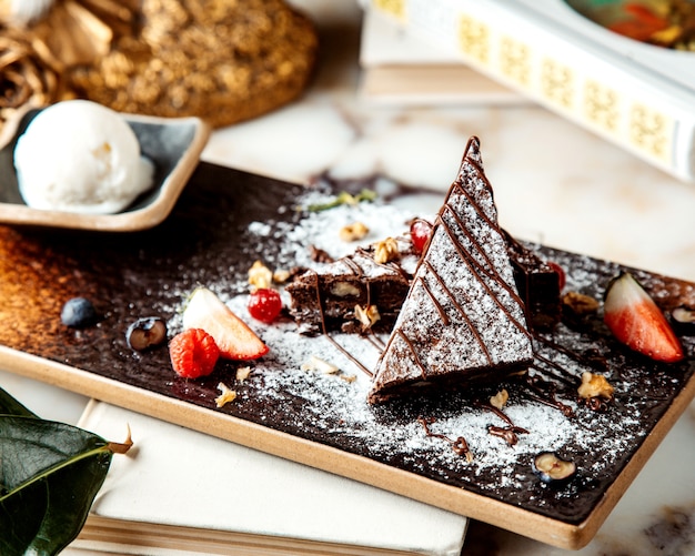 Chocolate cake with powdered sugar served with berries and ice cream