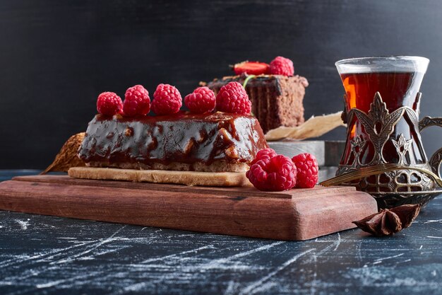 Chocolate cake with raspberries and a glass of tea. 