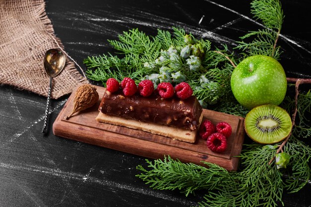 Chocolate cake with raspberries on wooden platter.