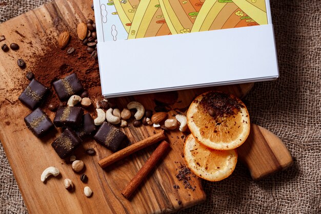 Chocolate candies cinnamon orange and nuts on wood desk.