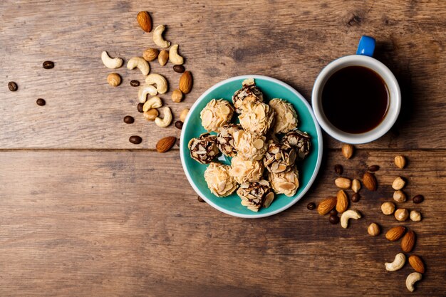 Chocolate candies coffee and nuts on wood