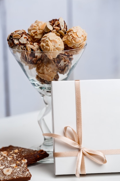 Chocolate candies in glass and box on white