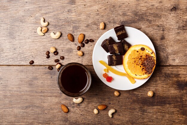 Foto gratuita caffè e noci arancio della cannella delle caramelle di cioccolato su legno