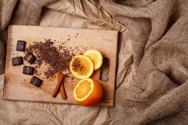 木製の机の上のチョコレートキャンディーオレンジとシナモン。