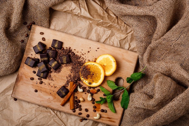 Foto gratuita cannella e noci di menta arancio delle caramelle di cioccolato sullo scrittorio di legno.