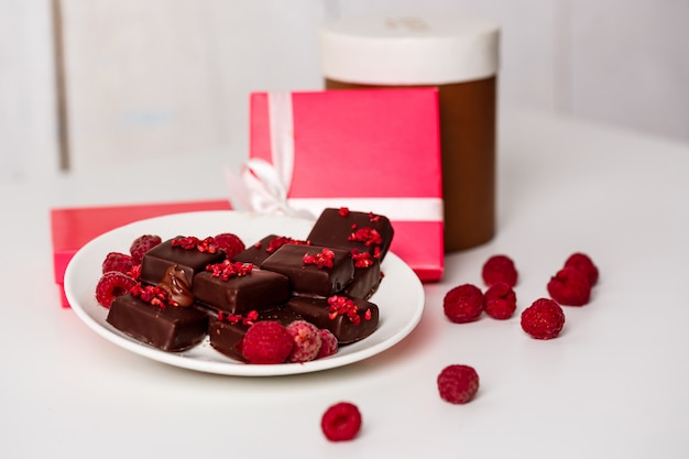 Chocolate candies and raspberry on white