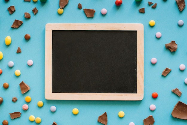 Chocolate and candy drops around chalkboard