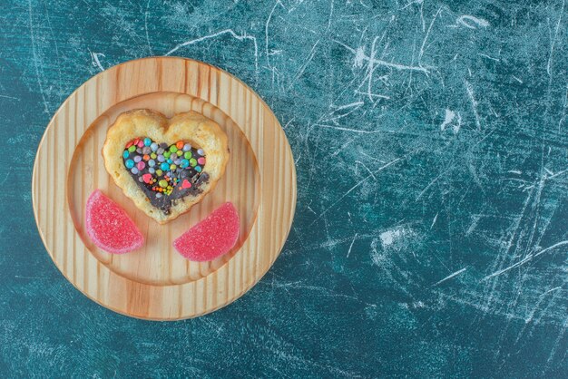 Chocolate and candy filled cake and marmelades on a wooden platter on blue background. High quality photo