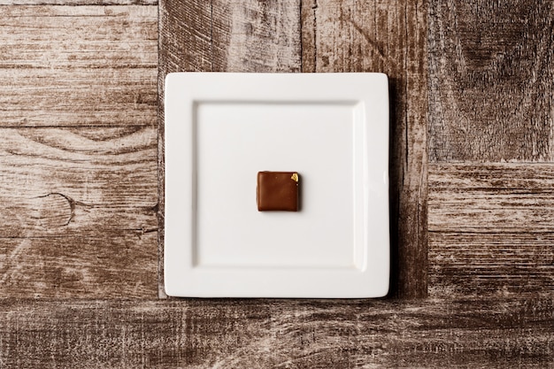 Chocolate candy on white plate on wooden